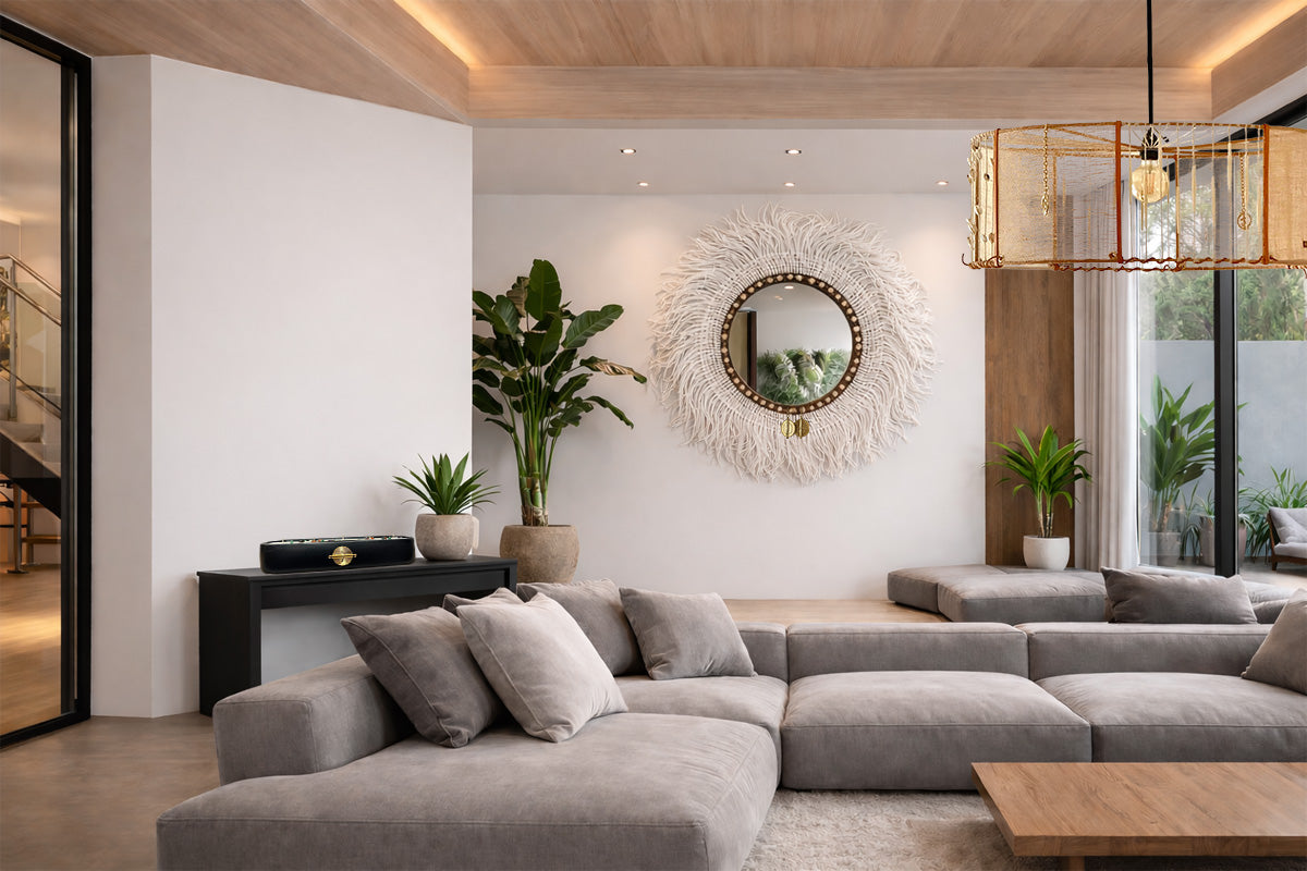 Salon lumineux décoré dans un style bohème chic avec un miroir mural artisanal MIYA en fibres naturelles au centre, entouré de plantes et d’un canapé contemporain.