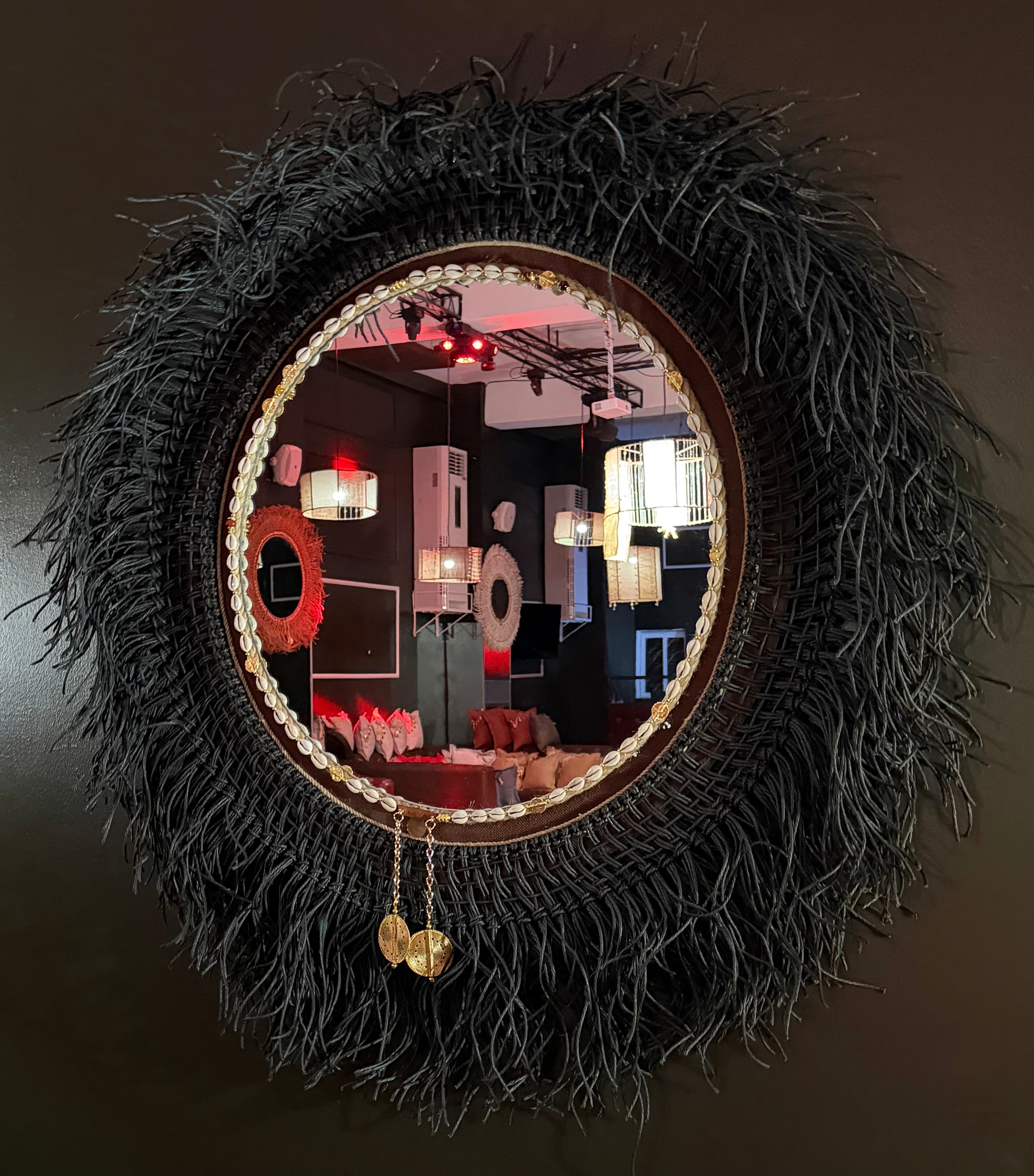 Miroir rond Ebony accroché à un mur dans un lounge  avec reflets - Décoration murale artisanale | MIYA